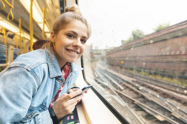 Portrait of smiling young woman travelling by train - WPEF01636