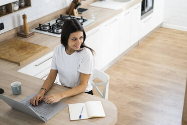 Smiling young woman using laptop at home - GIOF06932