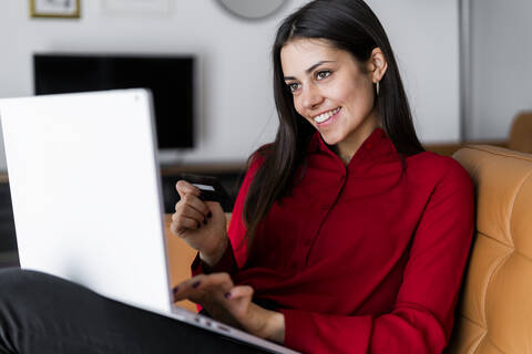 Glückliche junge Frau beim Online-Shopping zu Hause, lizenzfreies Stockfoto