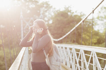 Teenager-Mädchen benutzt Smartphone und hört Musik auf einer Brücke - NMS00369