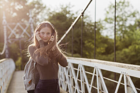 Teenager-Mädchen benutzt Smartphone und hört Musik auf einer Brücke, lizenzfreies Stockfoto