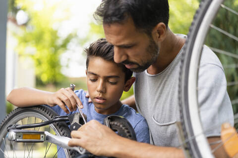 Vater und Sohn reparieren gemeinsam ein Fahrrad, lizenzfreies Stockfoto