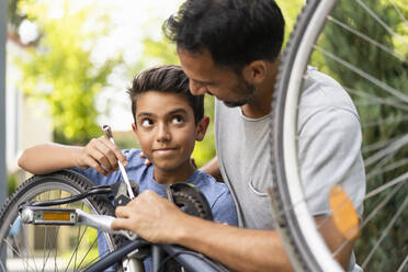 Father and son repairing bicycle together - DIGF07720
