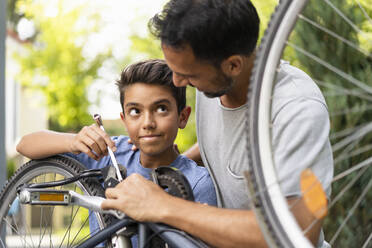 Vater und Sohn reparieren gemeinsam ein Fahrrad - DIGF07720