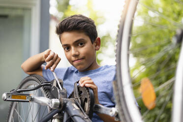 Porträt eines selbstbewussten Jungen, der sein Fahrrad repariert - DIGF07722