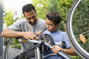 Father and son repairing bicycle together - DIGF07757