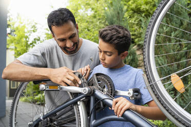 Vater und Sohn reparieren gemeinsam ein Fahrrad - DIGF07757