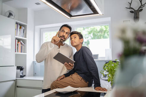 Father and son using tablet in kitchen - DIGF07770