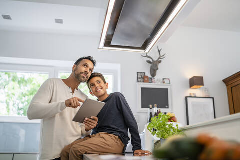 Vater und Sohn benutzen Tablet in der Küche, lizenzfreies Stockfoto