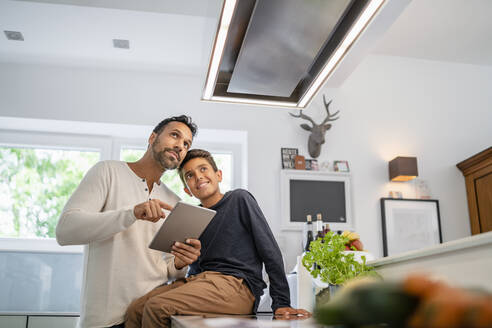 Father and son using tablet in kitchen - DIGF07771