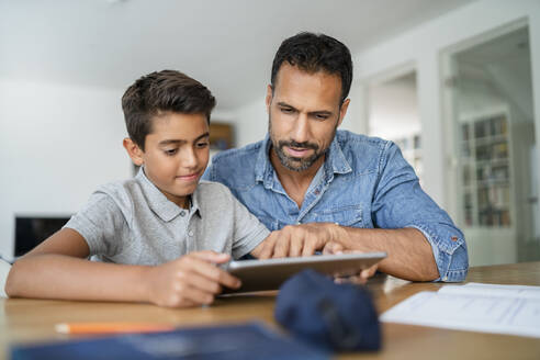 Vater und Sohn benutzen ein Tablet und machen Hausaufgaben - DIGF07788