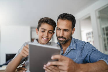 Vater und Sohn nutzen gemeinsam ein Tablet zu Hause - DIGF07790
