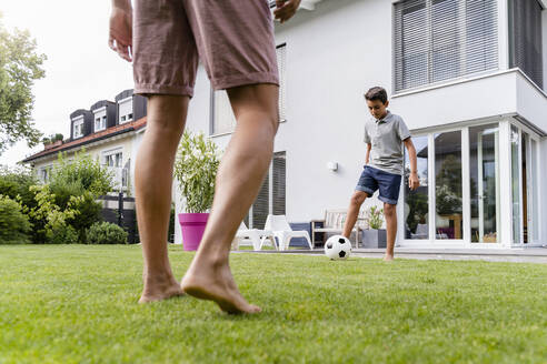 Vater und Sohn spielen Fußball im Garten - DIGF07793