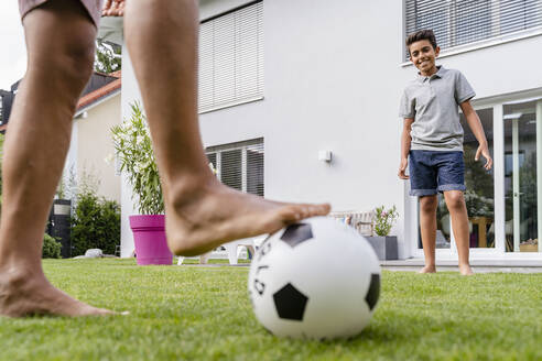 Vater und Sohn spielen Fußball im Garten - DIGF07794