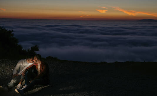 Homosexuelles Paar küssen in den Bergen über den Wolken bei Sonnenuntergang - LJF00517