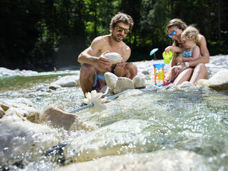 Family with daughter fixing water wheel in a mountain stream - CVF01365
