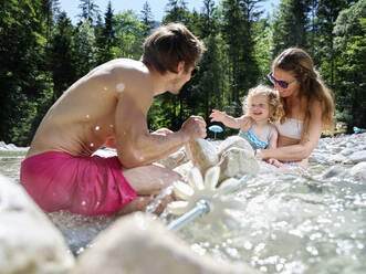 Familie mit Tochter repariert Wasserrad in einem Gebirgsbach - CVF01368