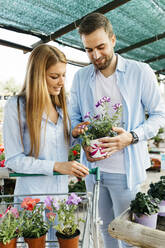 Happy couple buying flowers in a garden center - JRFF03444