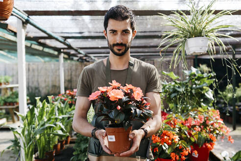 Porträt eines Gärtners in einem Gartencenter mit einer Blume - JRFF03477