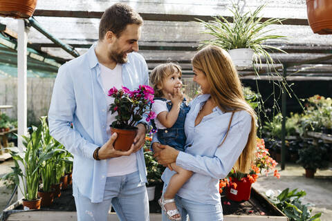 Glückliche Mutter, Vater und Tochter kaufen Blumen in einem Gartencenter, lizenzfreies Stockfoto