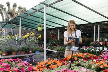 Mitarbeiterin in einem Gartencenter mit einem Tablet - JRFF03504