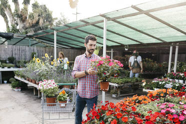 Kunde eines Gartencenters bei der Auswahl einer Blume - JRFF03508