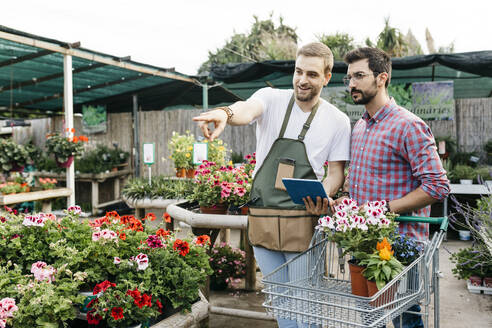 Arbeiter mit Tablet in einem Gartencenter, der Kunden berät - JRFF03518