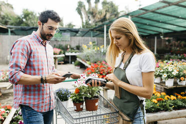 Kunde bezahlt mit Smartphone in einem Gartencenter - JRFF03539