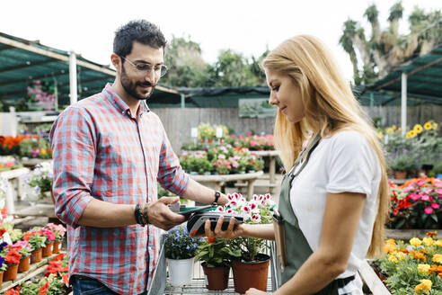 Kunde bezahlt mit Smartphone in einem Gartencenter - JRFF03540