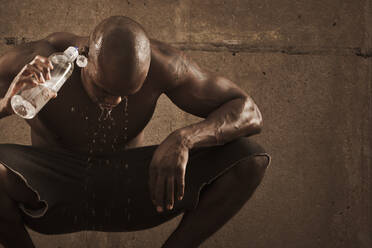 African American man pouring water over himself after exercise - BLEF12250