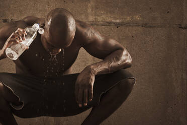 Afroamerikanischer Mann, der sich nach dem Sport mit Wasser übergießt - BLEF12250