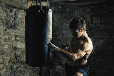 Kaukasischer Boxer trainiert und schlägt auf einen Sandsack - BLEF12266