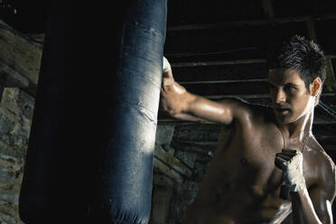 Kaukasischer Boxer trainiert und schlägt auf einen Sandsack - BLEF12268