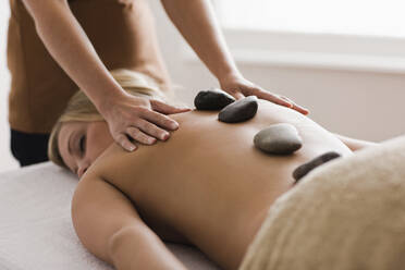 Caucasian woman receiving hot stone massage - BLEF12272