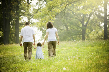 Parents walking with daughter in field - BLEF12279