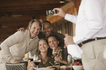 Man taking photographs of friends in restaurant - BLEF12294