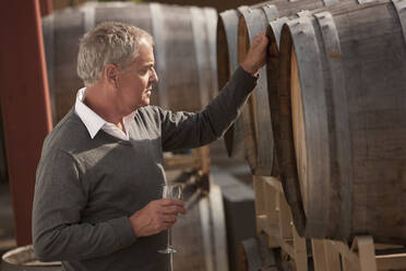 Caucasian man drinking wine near wine barrel - BLEF12307