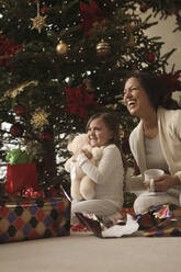 Mixed race mother and daughter opening gifts Christmas morning - BLEF12315