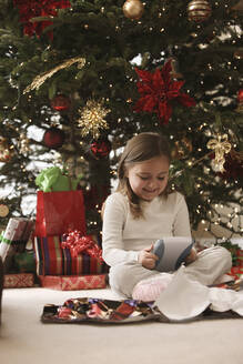 Gemischtrassiges Mädchen beim Öffnen der Geschenke am Weihnachtsmorgen - BLEF12318
