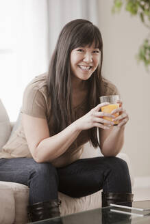 Asiatische Frau trinkt Orangensaft - BLEF12325