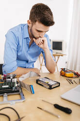 Techniker, der einen Desktop-Computer repariert und überlegt, wie er die Festplatte reparieren kann - JRFF03553