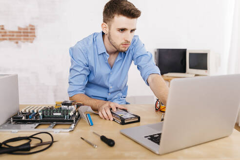 Techniker, der einen Desktop-Computer repariert, mit Laptop - JRFF03554
