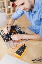 Technician repairing a desktop computer, checking the continuity of the plates and connectors - JRFF03558