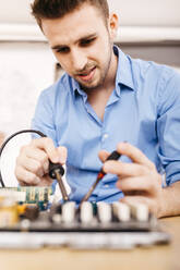 Technician repairing a desktop computer, soldering a component with tin - JRFF03564