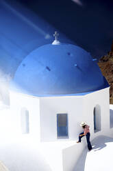 Woman on top of a blue dome church top, Santorini, Greece - DSGF01850