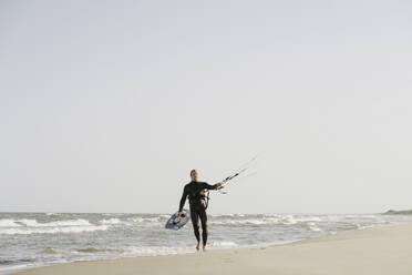 Kiteboarder beim Spaziergang mit seinem Kite am Strand - AHSF00717