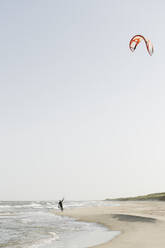 Kiteboarder beim Vorbereiten seines Kites am Strand - AHSF00728