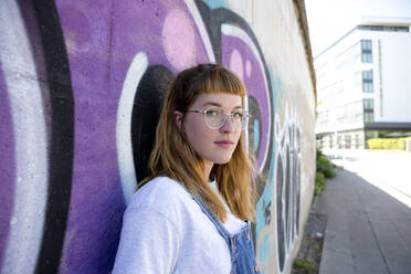 Junge Frau vor einem lila Graffiti - FLLF00248
