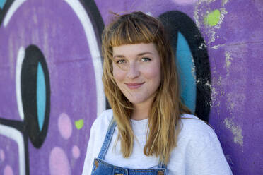 Junge Frau vor einem lila Graffiti - FLLF00252