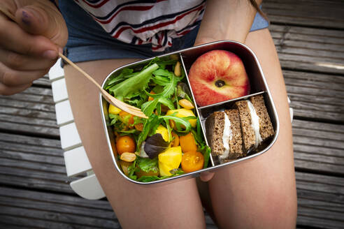 Mittelteil eines Mädchens, das gesund zu Mittag isst, während es auf einer Bank sitzt - LVF08220